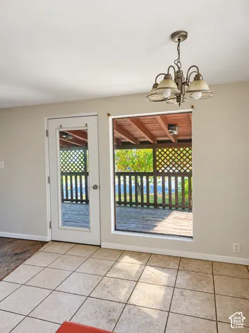 Tile flooring, glass-paneled door, large picture window, and covered outdoor deck area