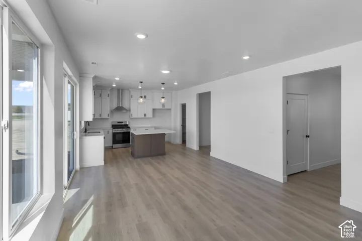 Kitchen featuring white cabinetry, stainless steel appliances, a center island with a white countertop, and pendant lighting