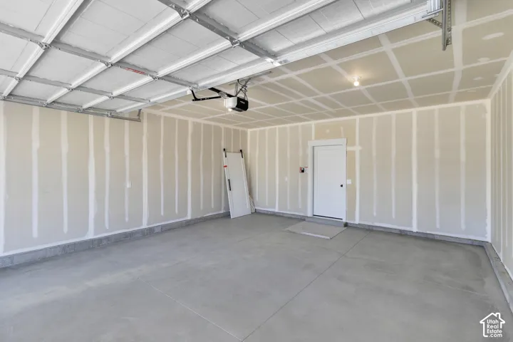Spacious garage with concrete flooring, automatic garage door opener, and a single entry door