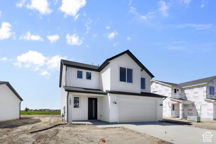 Two-story residence featuring white horizontal siding, vertical siding accents, a black roof, and an attached two-car garage