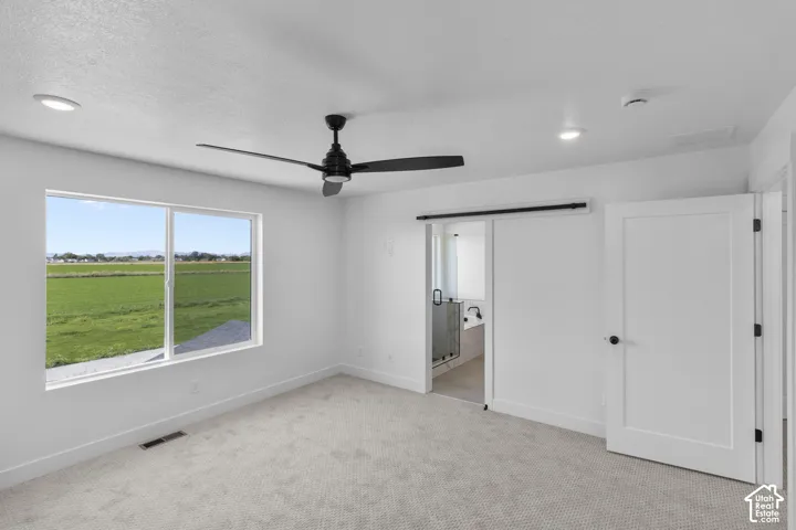 Recessed lighting, ceiling fan, sliding barn door, paneled interior door, and a large window with a landscape view