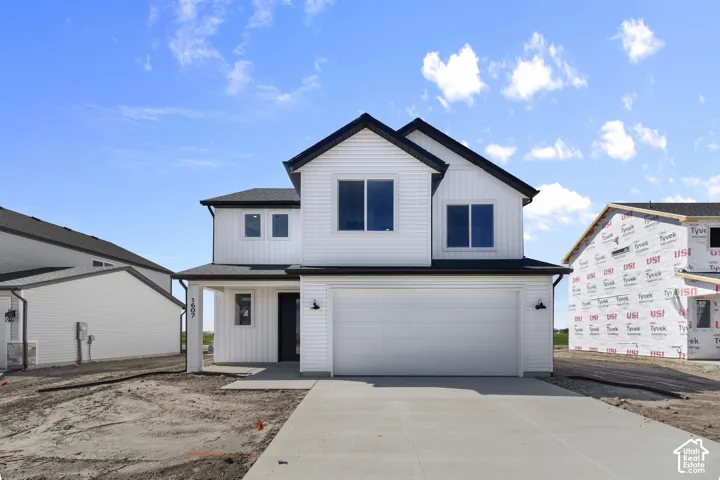 Two-story residence featuring white horizontal and vertical siding, a covered entry, a two-car garage, and dark-framed windows