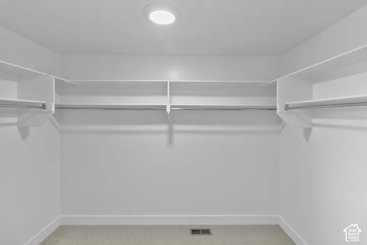 Recessed ceiling lighting, white shelving, metal hanging rods, and light-toned carpeting