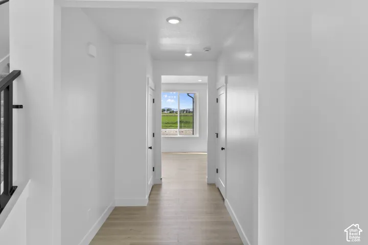 Recessed lighting illuminating a hallway with wood-finish flooring