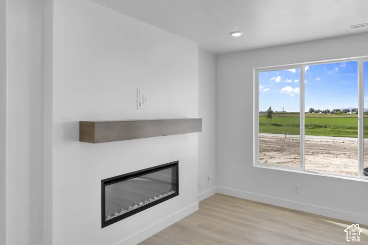 Recessed lighting, wood-finish flooring, electric fireplace with floating mantel, and large picture windows