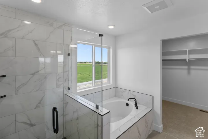Full-sized shower with glass enclosure, separate soaking tub, and natural light from the exterior window