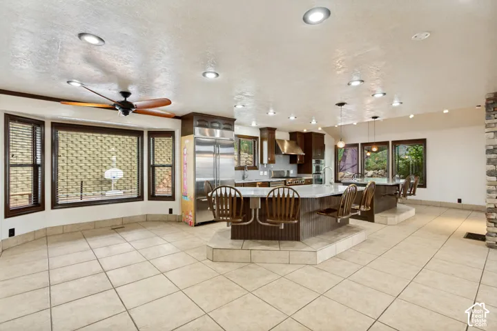 Spacious kitchen and dining area featuring recessed lighting, a stone accent wall, wood-finish cabinetry, and stainless steel appliances