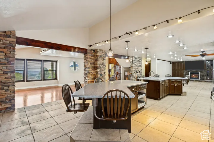 Expansive interior with vaulted ceilings, natural stone columns, tile flooring, and a fireplace with stone surround
