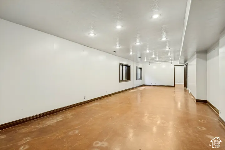 Expansive room featuring recessed ceiling lighting, light-colored walls, wood-finish trim, and multiple windows