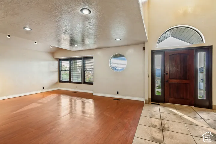 Recessed lighting, wood-finish flooring, and a large window with horizontal blinds