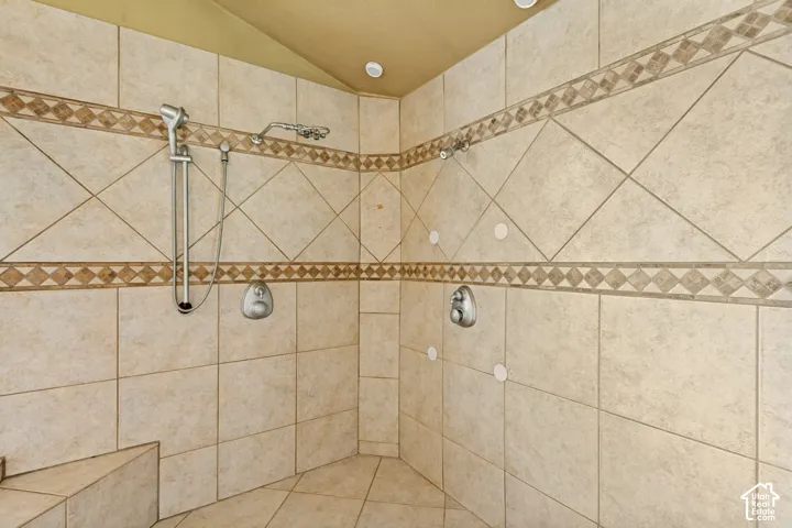 Tiled shower enclosure featuring a built-in bench, dual showerheads, and decorative accent banding