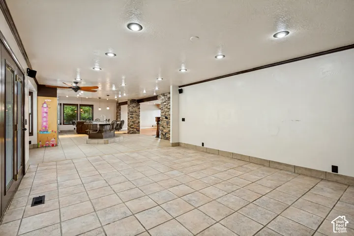 Expansive tiled flooring throughout, recessed lighting, and a built-in wet bar with seating