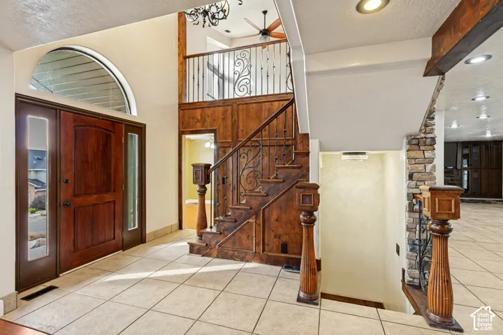 Tiled entryway with a wood-paneled staircase featuring wrought iron balusters and wood newel posts