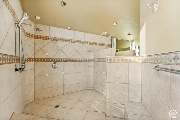 Spacious walk-in shower with neutral-toned tiling, decorative accent band, built-in bench, and dual shower heads
