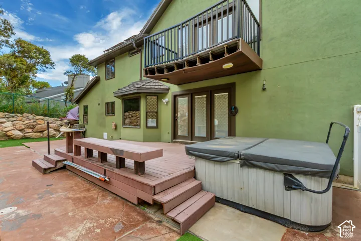 Expansive patio area featuring a hot tub, wood-finish decking with built-in seating, and a rock retaining wall