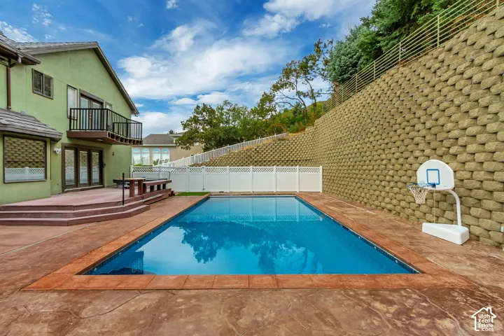 In-ground swimming pool with stamped concrete surround, terraced retaining wall, and an exterior balcony