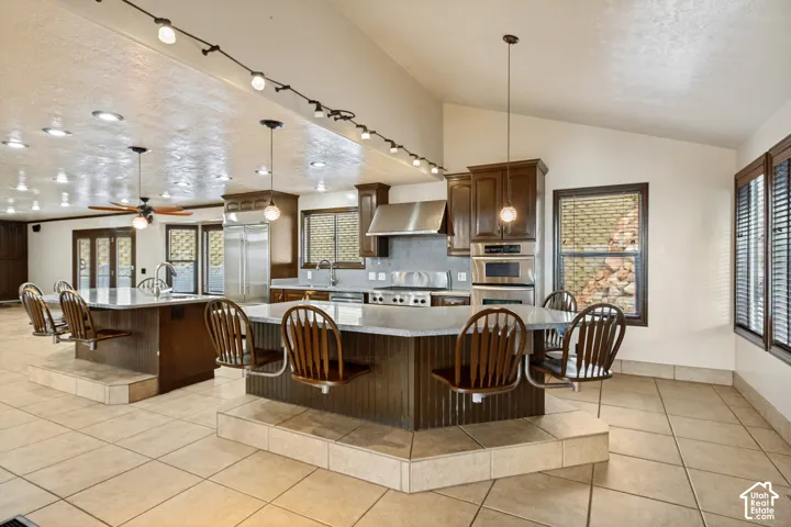 Spacious kitchen featuring two large islands with integrated seating, extensive cabinetry, stainless steel appliances, and tile flooring