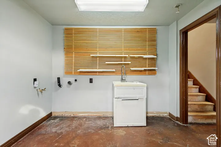 White utility sink with integrated faucet, light-toned walls, and wood-toned trim