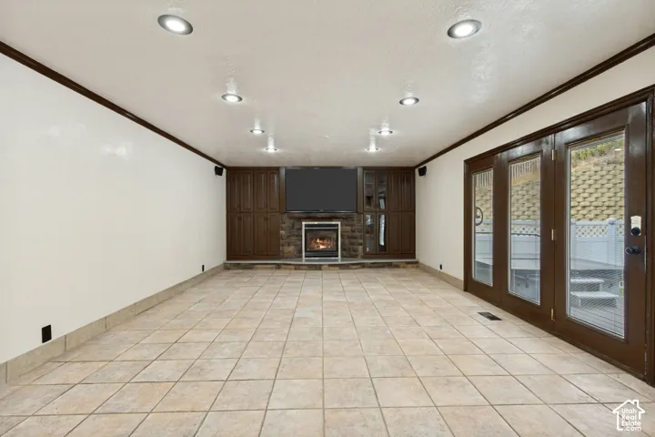 Tile flooring, recessed lighting, built-in cabinetry, stone fireplace, and double glass doors
