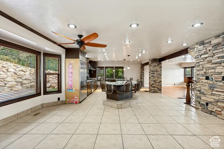 Spacious kitchen and dining area featuring tile flooring, recessed lighting, stone accent walls, and a built-in island