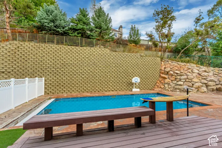 Outdoor swimming pool with a stone retaining wall and a wood-finish deck