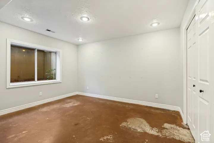 Recessed ceiling lighting, a window with white trim, and white bi-fold closet doors with black hardware