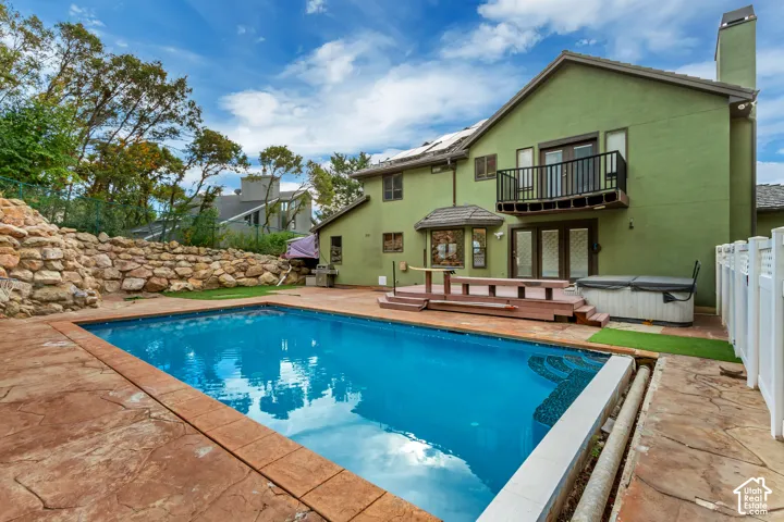 Backyard oasis featuring a swimming pool with stamped concrete surround, a multi-level wooden deck, and a built-in hot tub