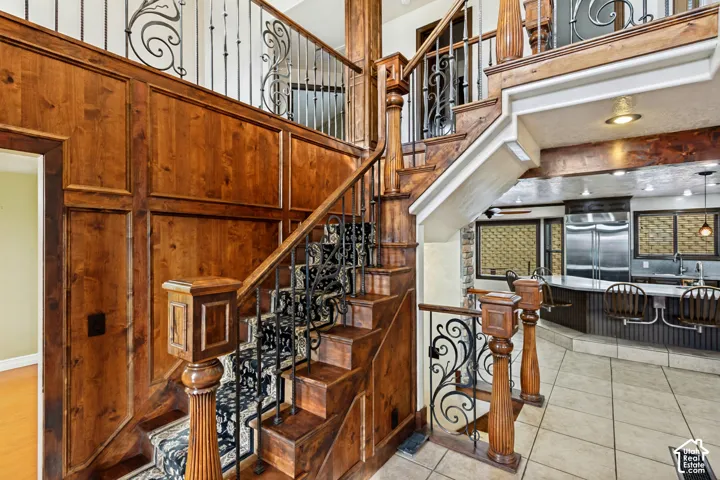 Hardwood staircase with ornate wrought iron balusters and wood paneling