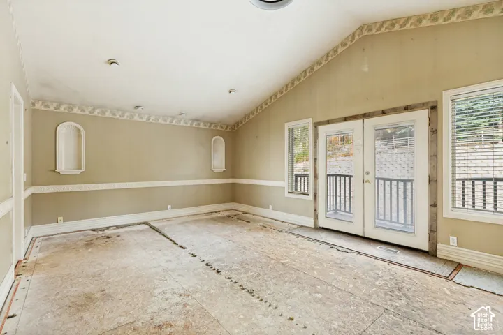 Vaulted ceiling, recessed lighting, double French doors, two built-in wall niches, and window blinds
