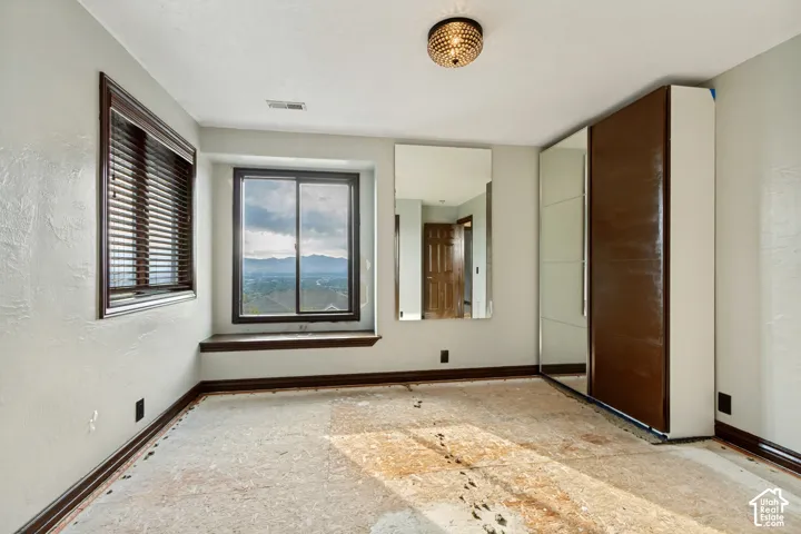 Built-in mirrored wardrobes, dark wood-finish window trim, ceiling-mounted light fixture, and large window with exterior scenery
