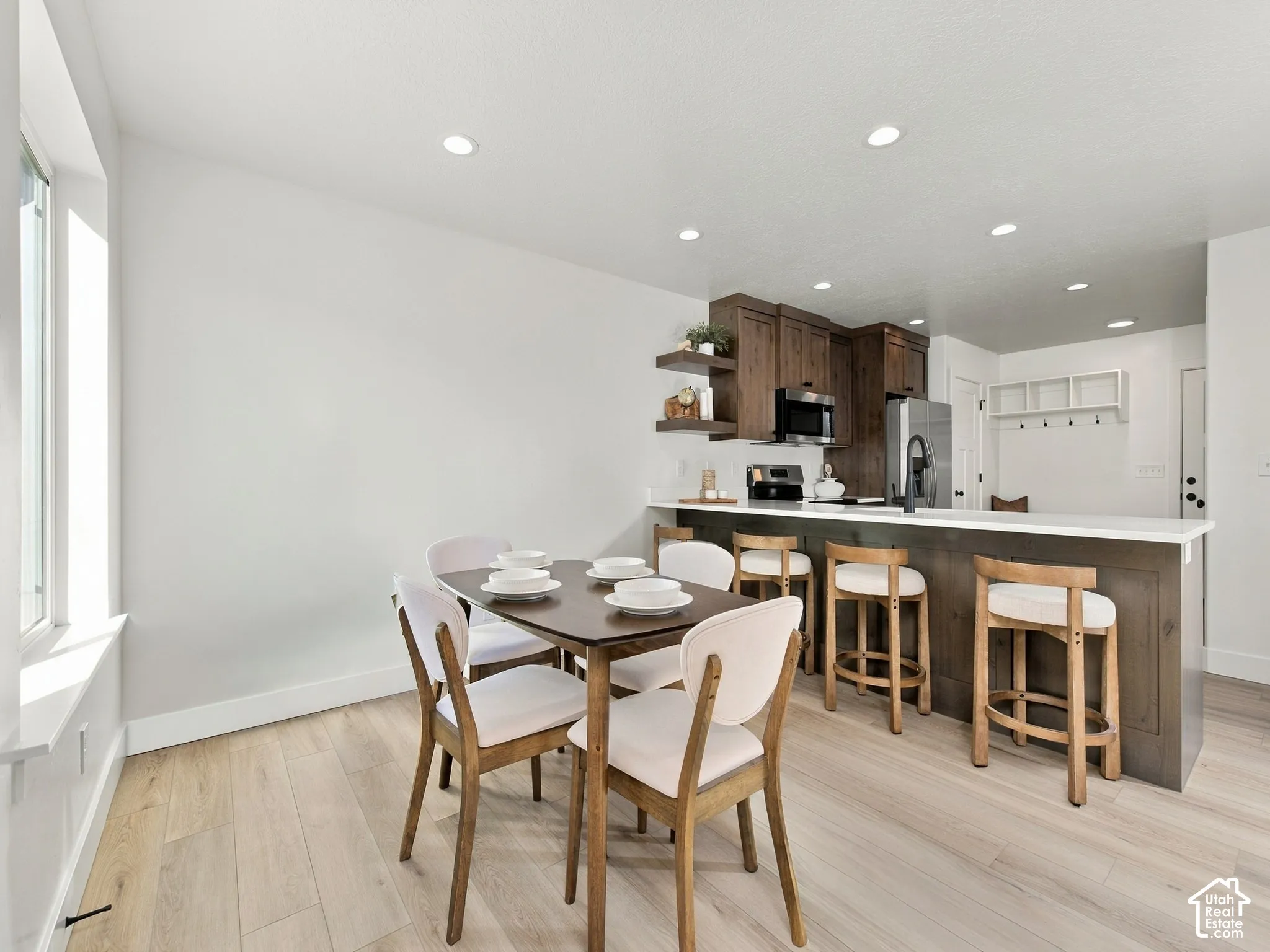 Recessed lighting, wood-finish flooring, dark wood cabinetry, white countertops, and stainless steel appliances