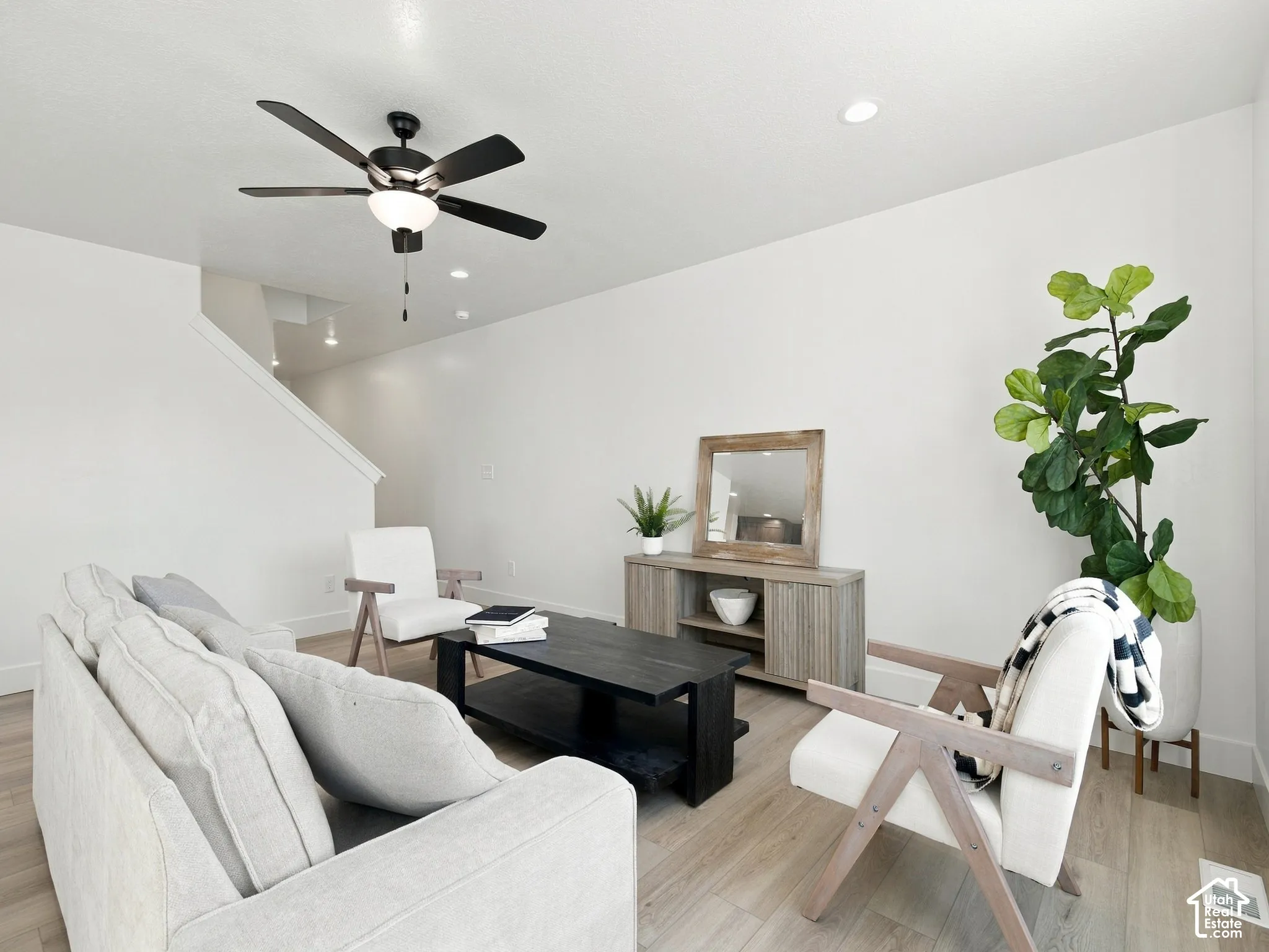 Recessed lighting, wood-finish flooring, staircase with a handrail, and a black ceiling fan with an integrated light