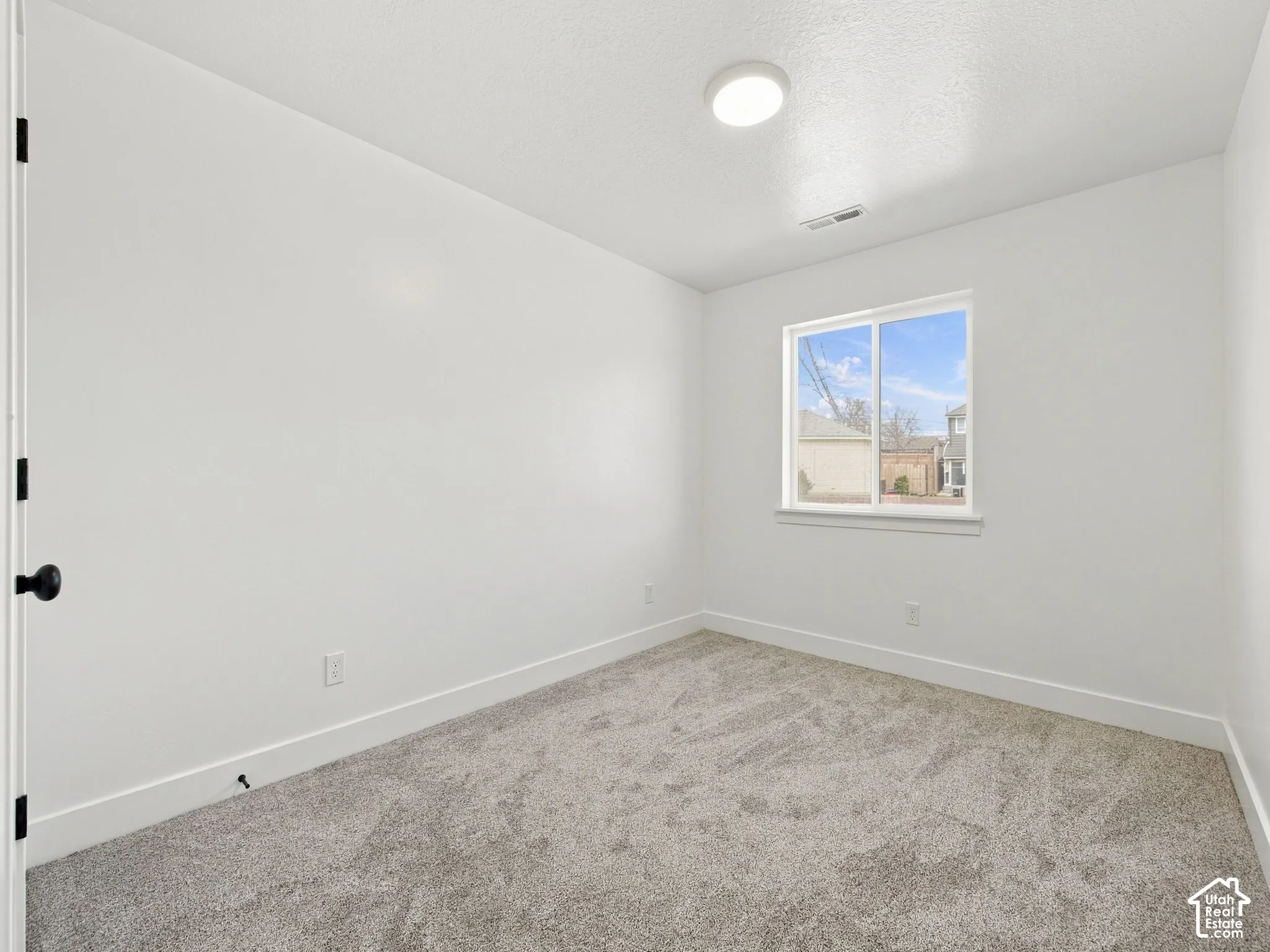 Neutral-toned carpeting, white walls, and a window with white trim