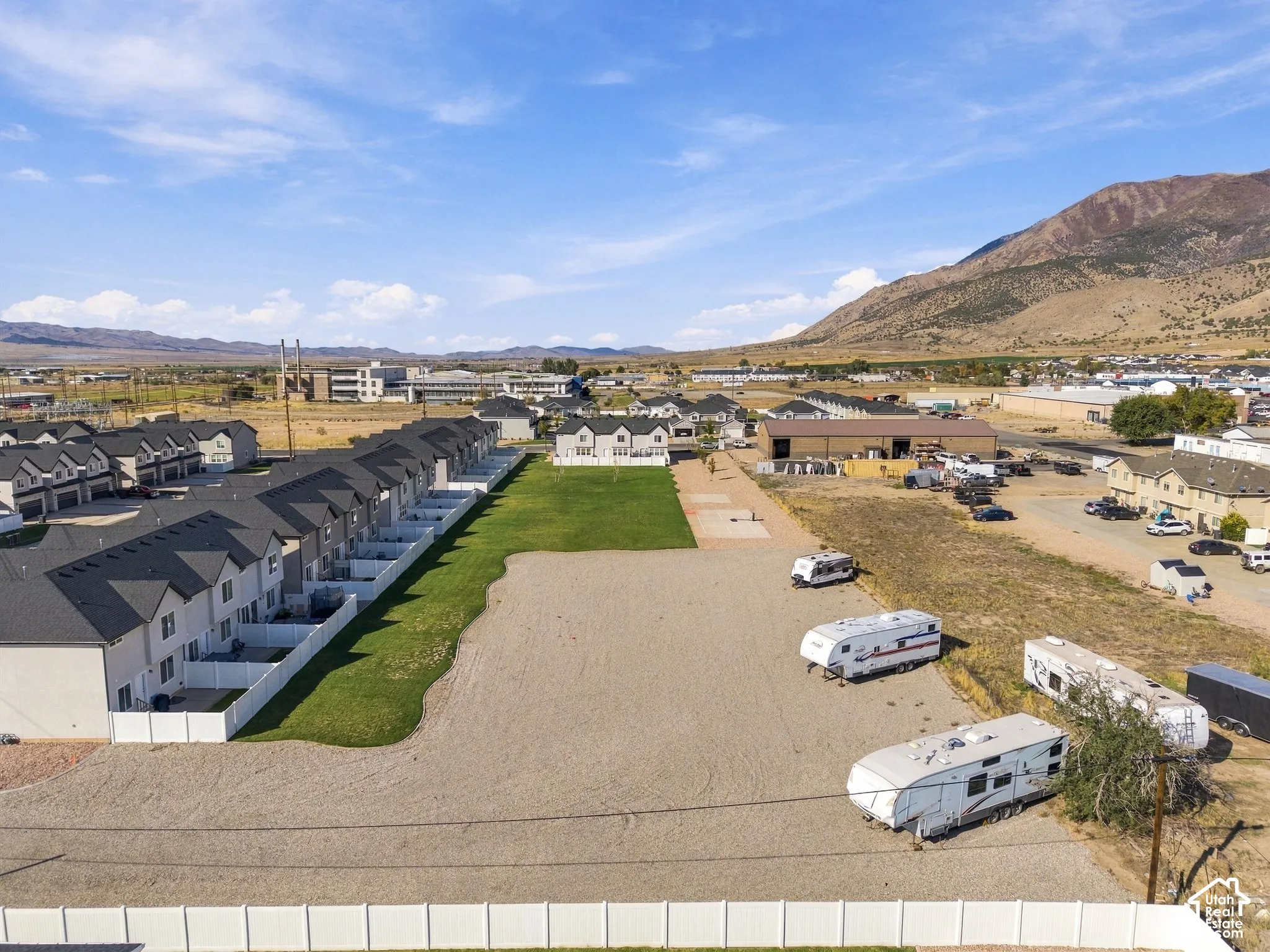 Row of townhome-style residences with white fencing and individual grass plots