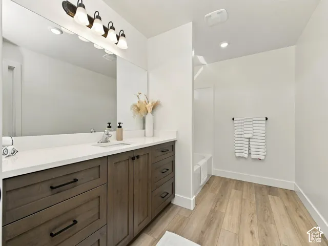 Bathroom featuring a long wood-finish vanity with a white countertop, rectangular undermount sink, and a large wall-mounted mirror