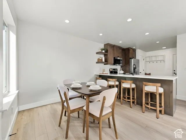 Recessed lighting, wood-finish flooring, dark wood cabinetry, white countertops, and stainless steel appliances