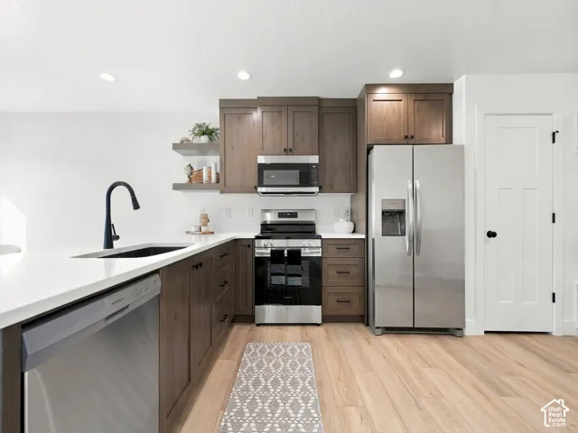 Kitchen featuring wood-finish flooring, stainless steel appliances, white countertops, dark wood-finish cabinetry, and recessed lighting
