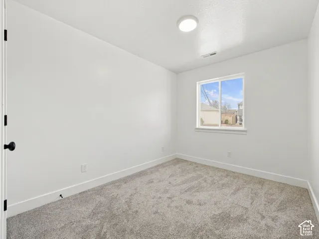 Neutral-toned carpeting, white walls, and a window with white trim