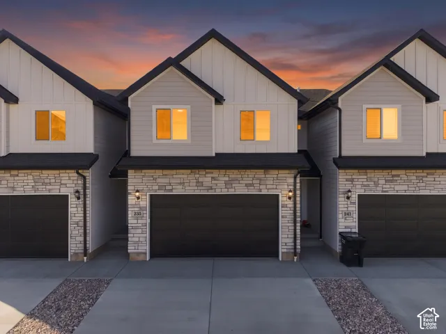 Townhome exterior featuring board and batten siding, stone veneer accents, and dark pitched roofs