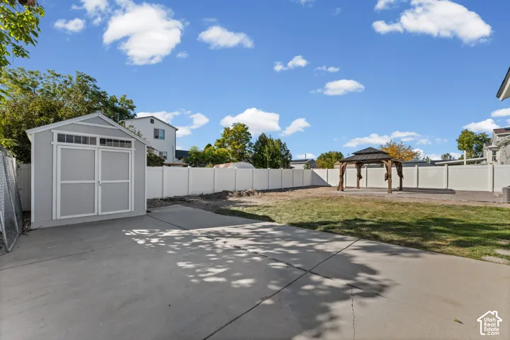 Spacious concrete patio, large storage shed, white privacy fencing, and an outdoor gazebo structure with a hardtop roof