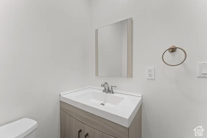 Vanity with integrated sink, wood-finish cabinetry, and brushed nickel hardware