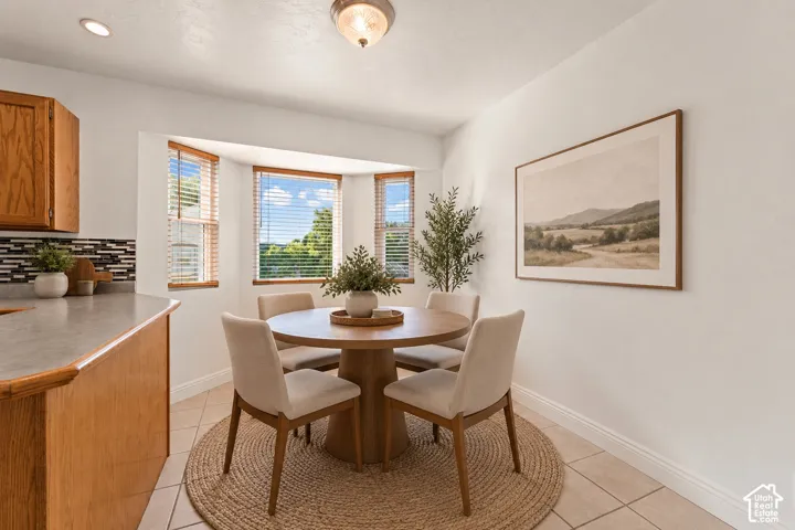 Bay window with wood-finish blinds, tiled flooring, wood-finish cabinetry, and a mosaic tile backsplash