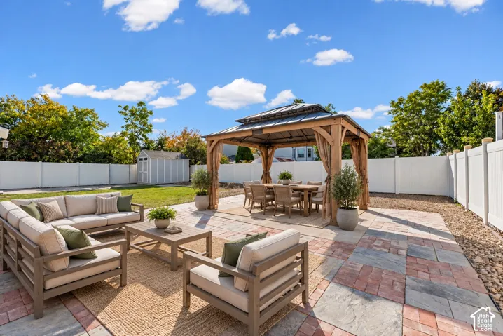 Expansive backyard featuring a multi-toned paver patio, a wooden gazebo, a manicured lawn, and white privacy fencing