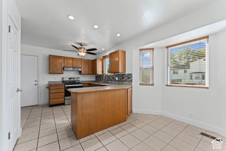 Kitchen featuring wood cabinetry, stainless steel appliances, tile flooring, and a breakfast bar