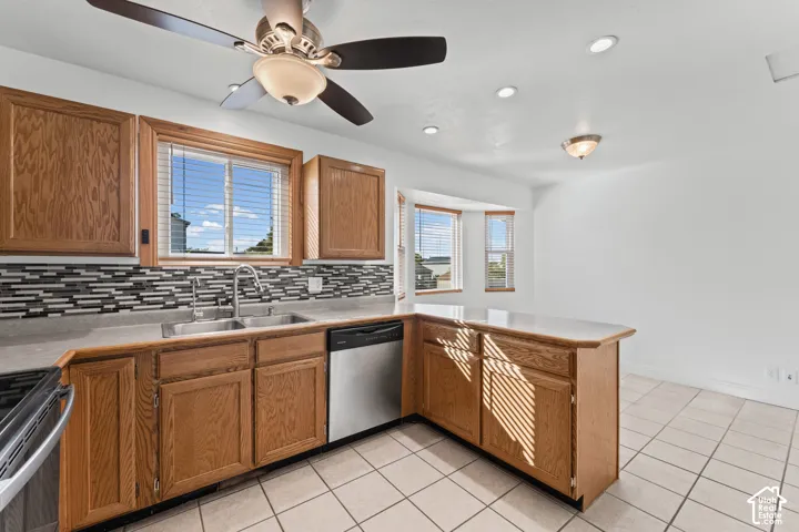 Kitchen featuring wood cabinetry, stainless steel sink, patterned tile backsplash, and recessed lighting
