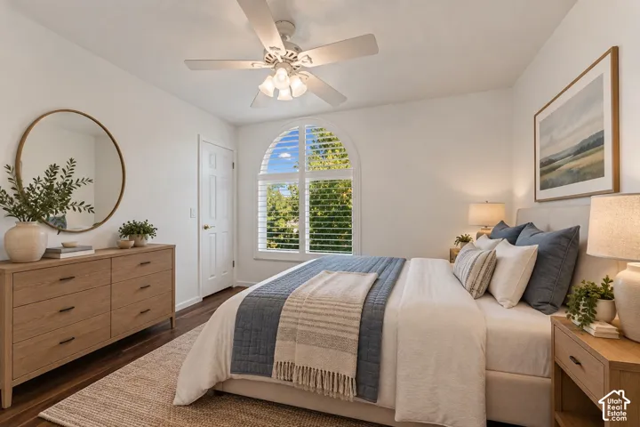 Arched window with plantation shutters, wood-finish flooring, white ceiling fan, white paneled door, and neutral wall color