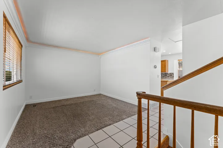 Spacious interior with neutral carpeting, crown molding, and a wood-finish handrail
