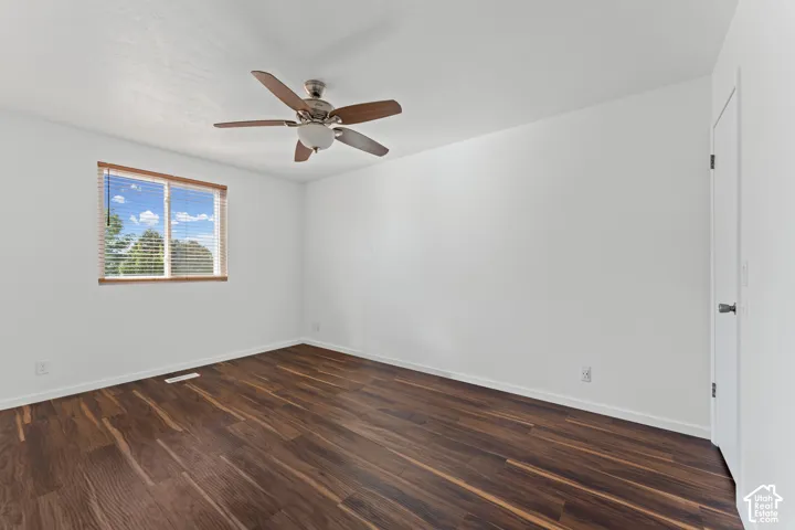 Wood-finish flooring, ceiling fan with integrated lighting, wood-trimmed window with blinds, and white door