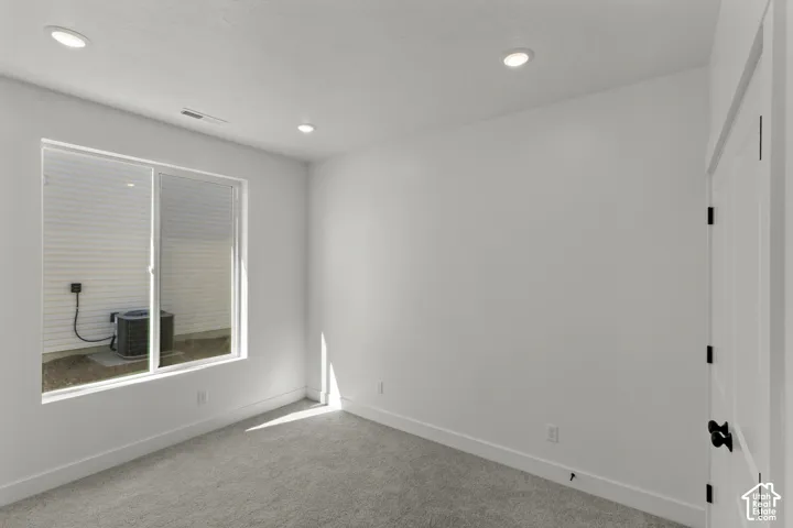 Carpeted room with recessed lighting, a sliding window, and a paneled door with black hardware