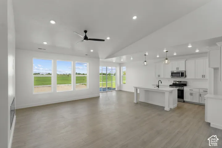Spacious open-concept living area featuring a vaulted ceiling with recessed lighting and a ceiling fan